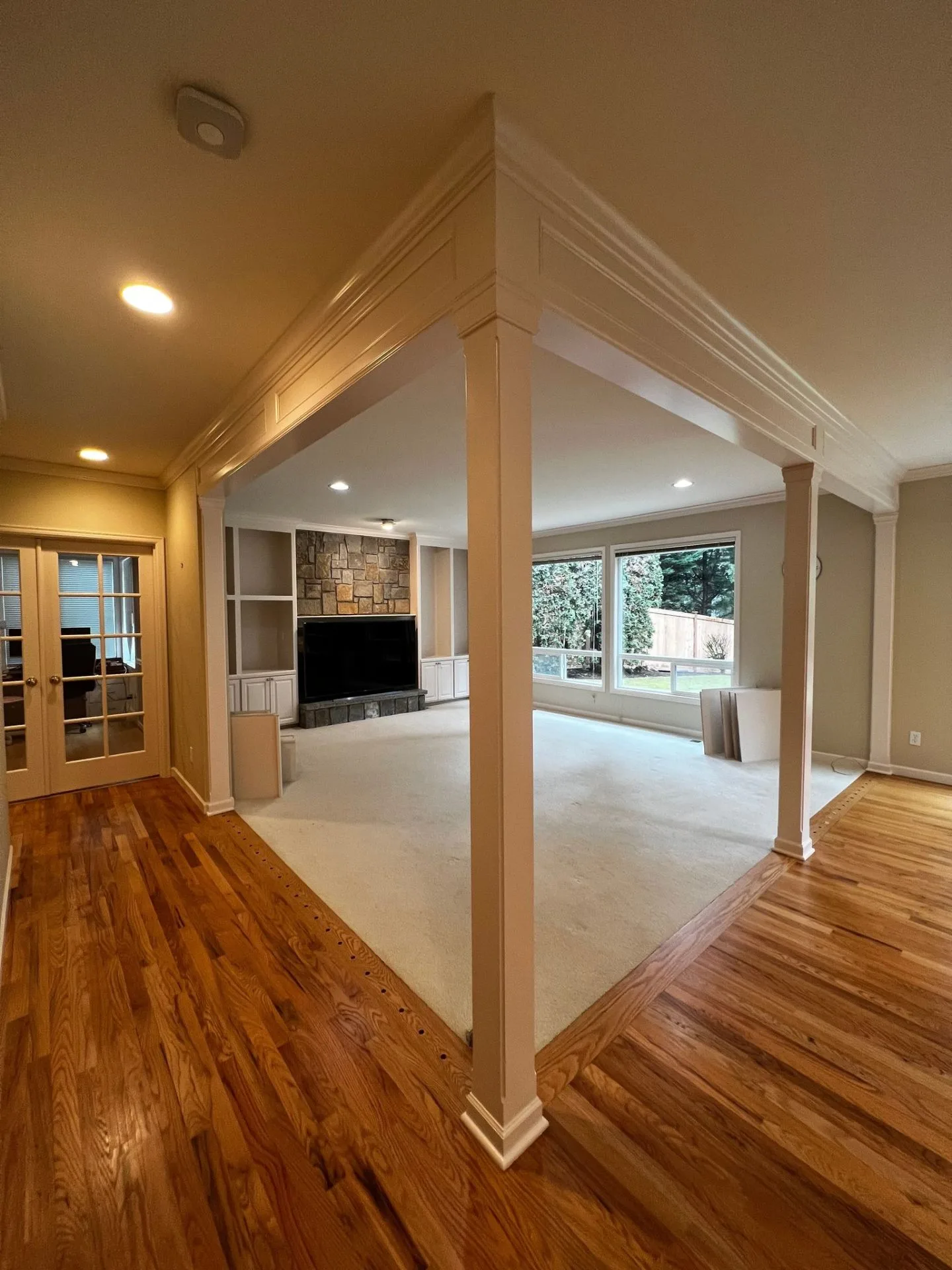 Open concept living space with painted columns and crown molding