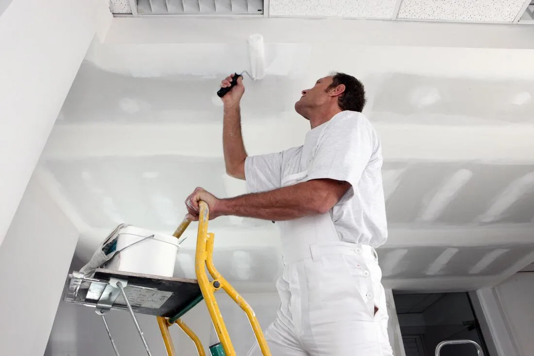 Painter rolling smooth finish on ceiling after removal