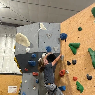 Climber resetting his footing partway up the bouldering wall